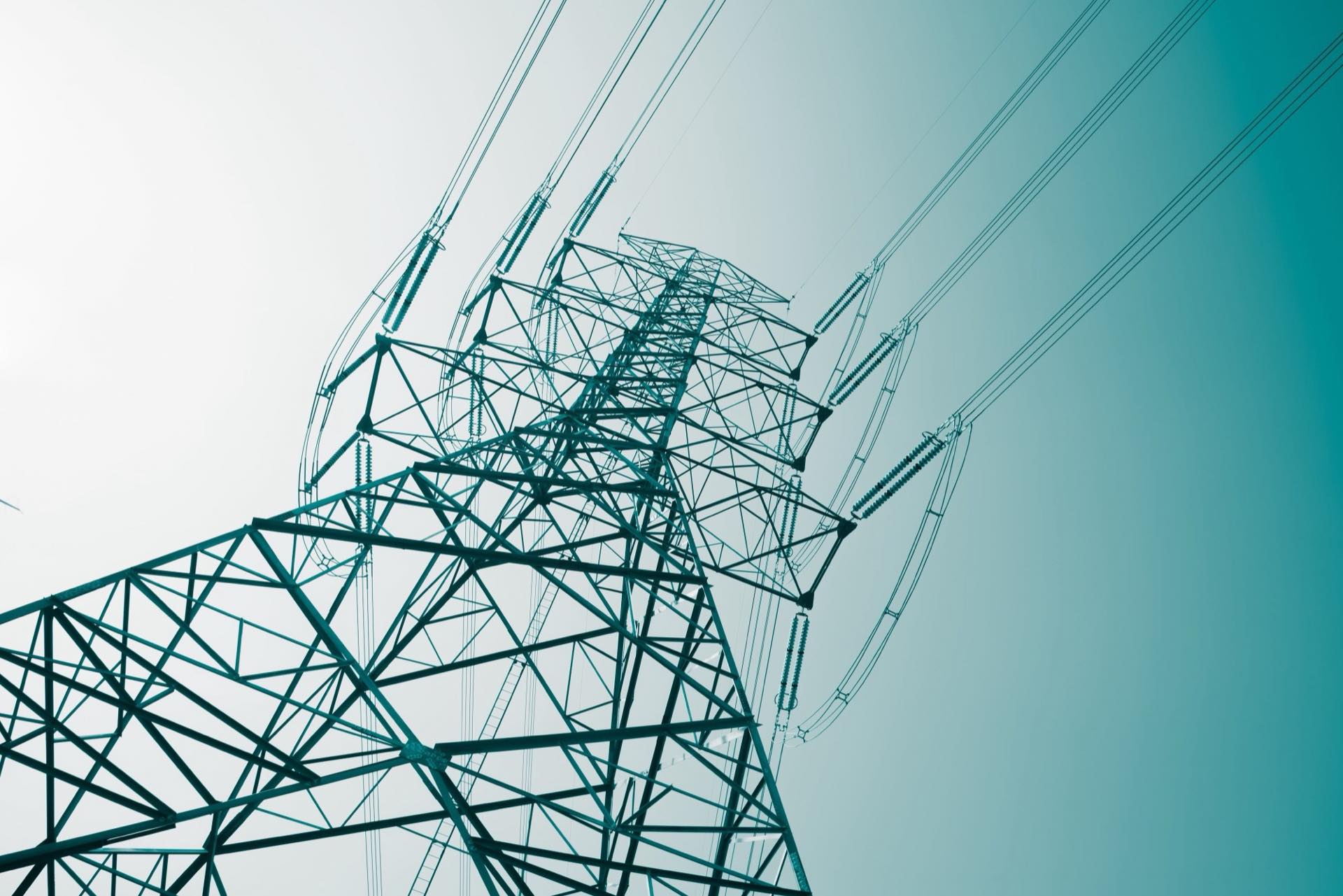 Hochspannungsmast eines Schweizer Energieversorgers vor hellem Himmel